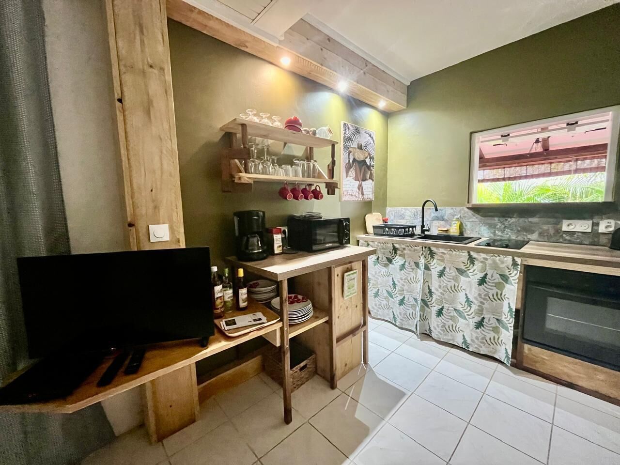 Uma cozinha compacta com bancada de madeira, micro-ondas, máquina de café e uma pia pequena.
