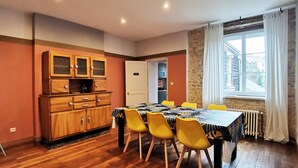 A dining area with a wooden cabinet, a table with a patterned tablecloth, and yellow chairs. - Ô charme - 105m² apartment 15 min from Orléans (Olivet)