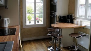 A compact kitchen with a wooden countertop, a built-in oven, and a window with a view of greenery. - Ô charme - 105m² apartment 15 min from Orléans (Olivet)
