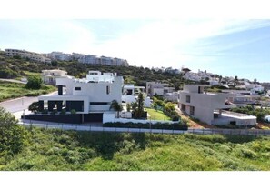 Ein moderner Wohnkomplex mit mehreren weißen Gebäuden, umgeben von Grünflächen und einer hügeligen Landschaft.