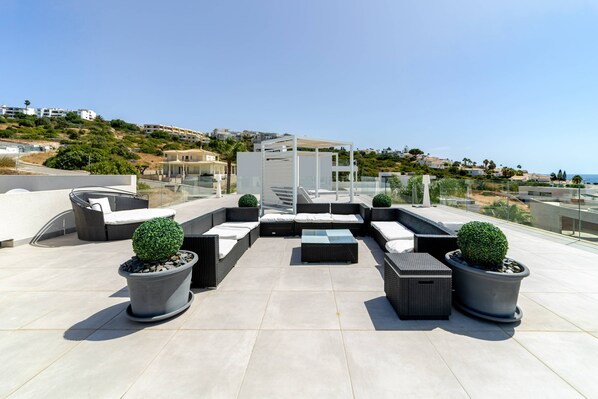 Une terrasse sur le toit, aménagée avec des espaces de détente en plein air, des plantes en pot et offrant une vue sur le paysage environnant.