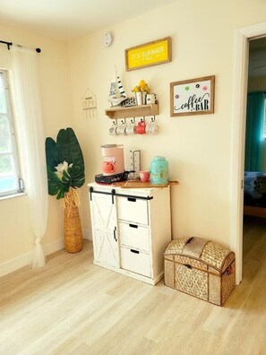 Une pièce avec un meuble en bois, un panneau indiquant un bar à café et une grande plante.