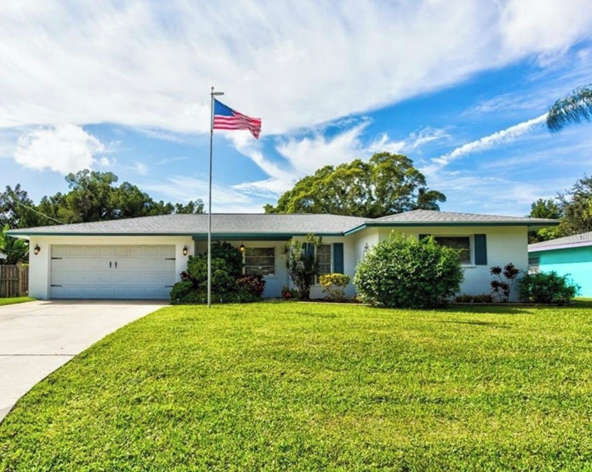 Et etplanshus med garage, græsplæne og et amerikansk flag.