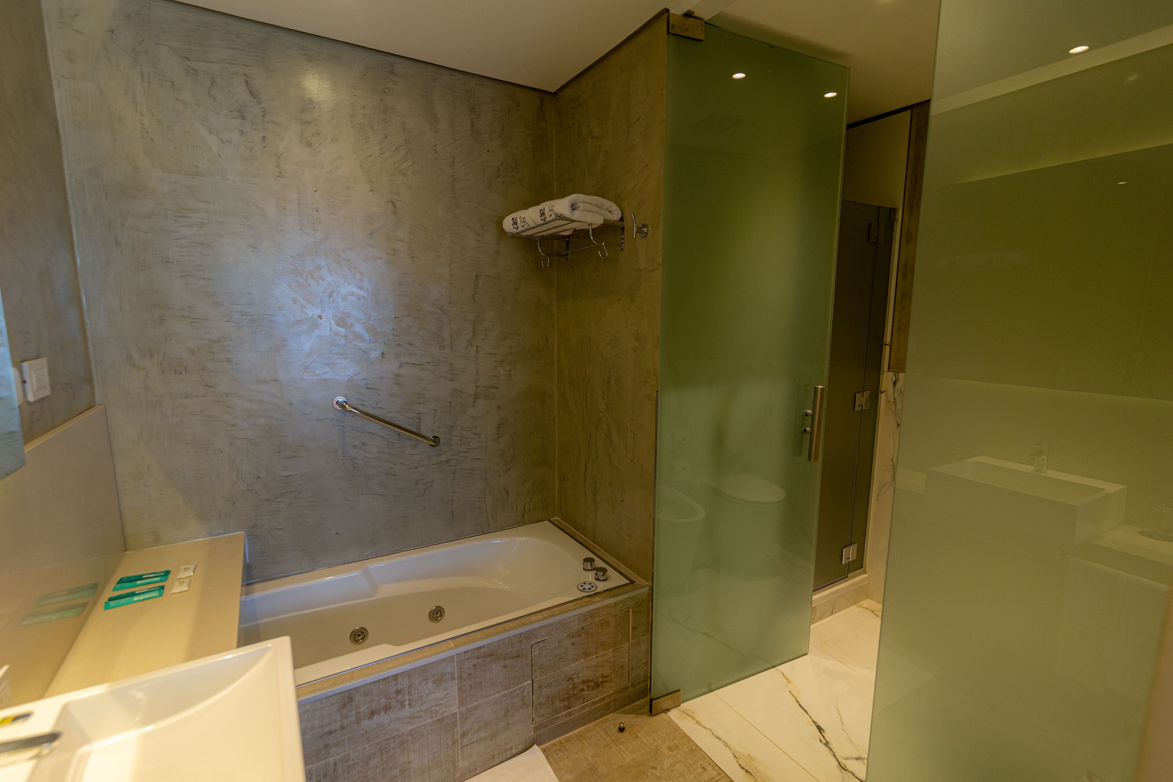A modern bathroom with a glass shower enclosure, a bathtub, and a separate sink area.