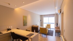 Une chambre d’hôtel moderne dotée d’une kitchenette, d’un coin repas et d’un espace de vie comprenant un canapé et des fauteuils.