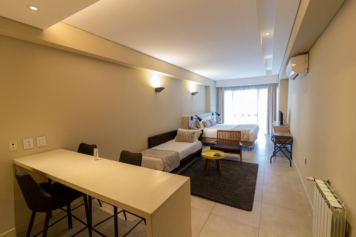Una habitación de hotel moderna con cama, escritorio y zona de comedor.