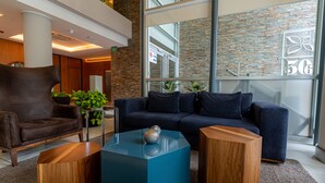 Un hall d’entrée moderne avec un canapé bleu foncé, des fauteuils en bois et une table basse bleue.