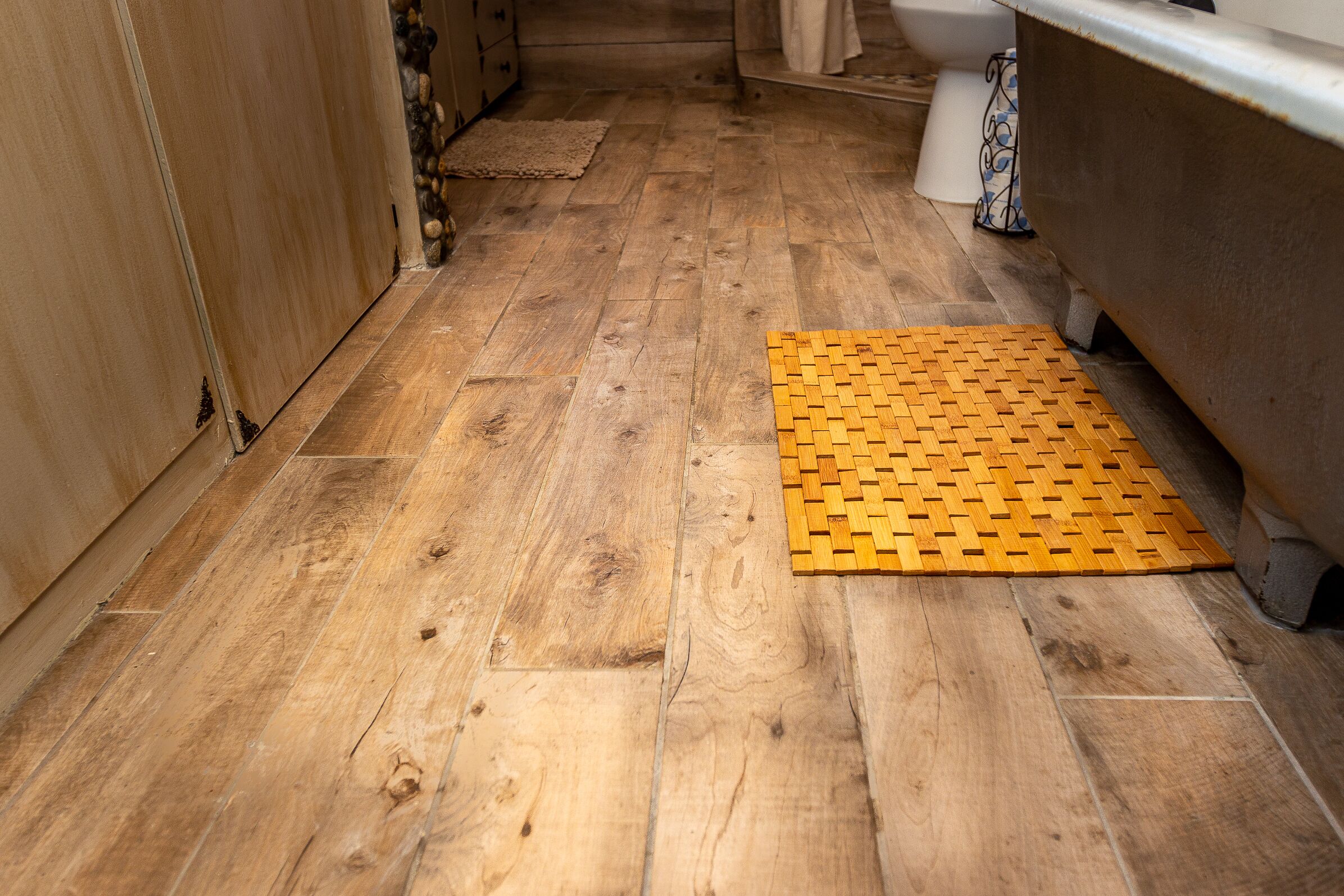 Un suelo de madera con un tapete tejido amarillo en un baño.