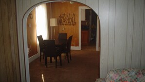 A room with a dining area, a bed, and a door leading to another room. - The Little Sunflower (Jetmore)