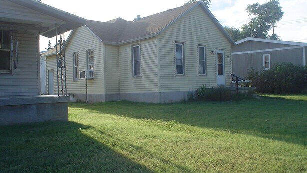 A single-story house with a front porch and a small front yard. - The Little Sunflower (Jetmore)