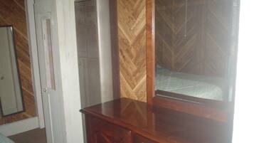 A room with a wooden dresser, a mirror, and a vent.