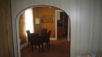 Una habitación con zona de comedor, cama y puerta que da a otra habitación.