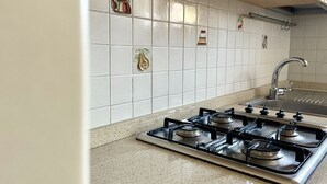 A kitchen with a gas stove, a sink, and decorative tiles on the wall. - S256 - Sirolo, comfortable apartment in the center (Sirolo)