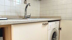 A kitchen with a stainless steel sink, a built-in washing machine, and a tiled backsplash. - S256 - Sirolo, comfortable apartment in the center (Sirolo)