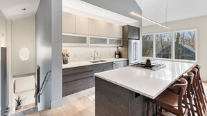 A modern kitchen with a large island, built-in appliances, and a view of the outdoors.