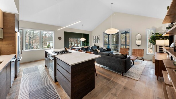 A spacious living area with a kitchen, a dining area, and a large window providing natural light.