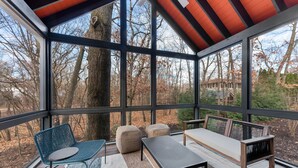 A covered outdoor seating area with a view of trees and a house.