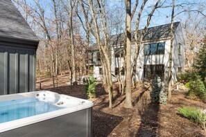 Un jacuzzi dans un jardin, avec une maison et des arbres.