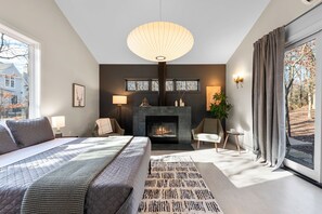 Une chambre moderne avec un grand lit, une cheminée et une vue sur l’extérieur.