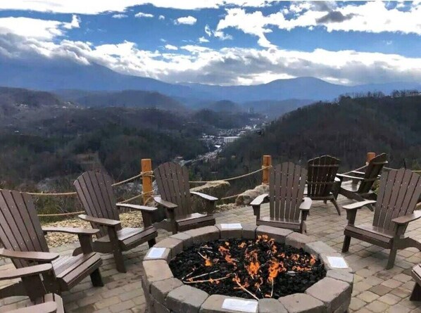 Un foyer avec des chaises disposées autour, offrant une vue sur une vallée et des montagnes à l’horizon.