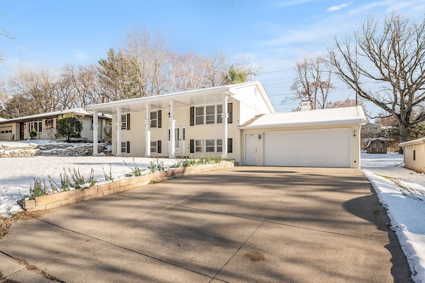 A two-story house with a garage, a covered porch, and a snow-covered driveway.