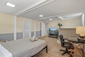 A hotel room with a bed, a desk with a chair, a TV, and a fireplace.