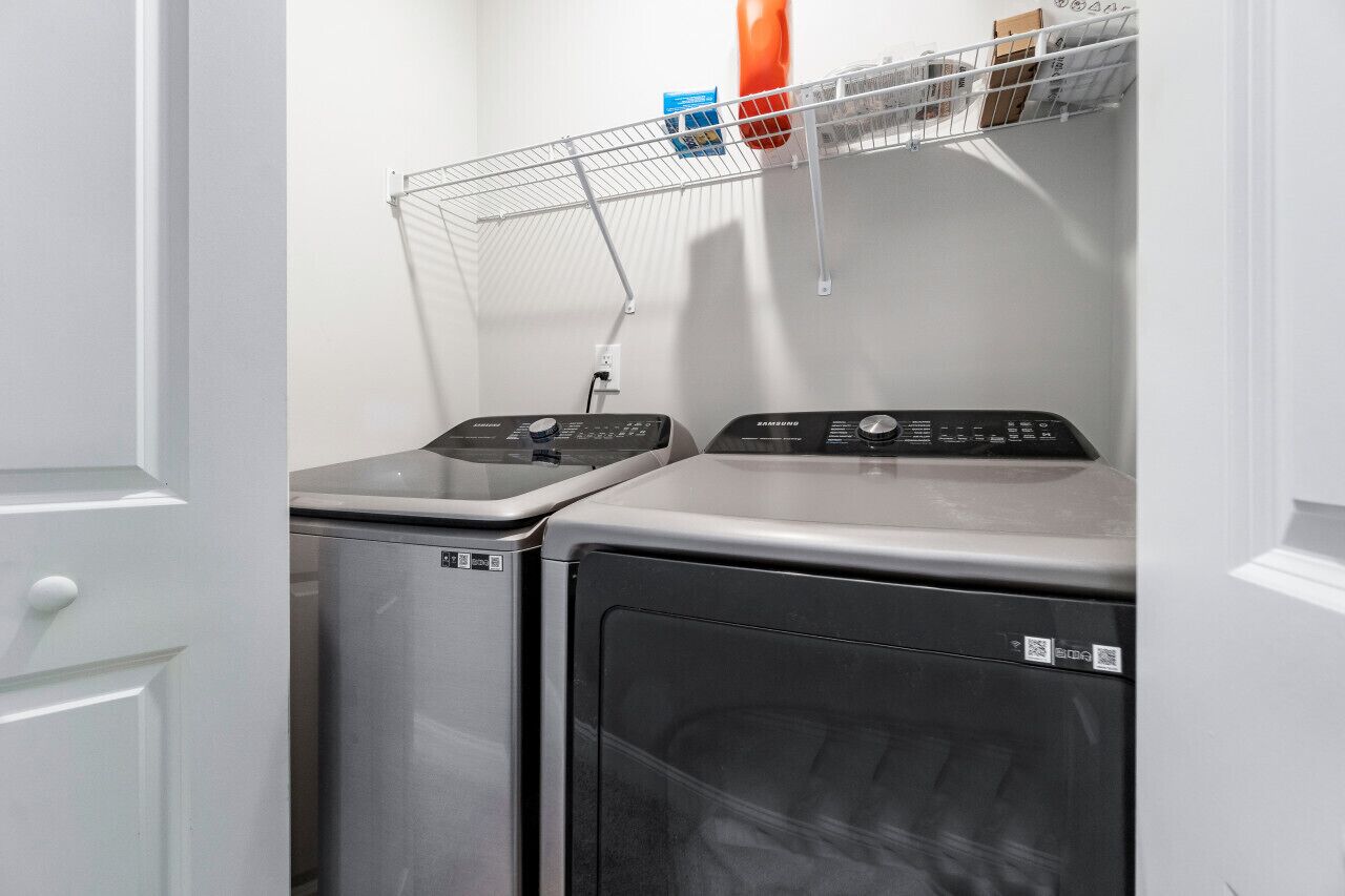 A laundry area with two washing machines and a drying rack.