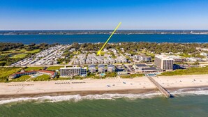 Luchtbeeld van een kustresort met meerdere gebouwen, een strand en een pier.
