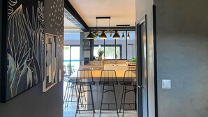 A modern kitchen with bar stools, a large black and gold artwork, and a sign reading "WELCOME". - Carcalove - Pool, Billard & Jacuzzi - 10pax (Fontiès-d'Aude)
