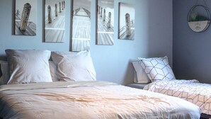 A bedroom with a large bed, two smaller beds, and a wall with framed artwork. - Carcalove - Pool, Billard & Jacuzzi - 10pax (Fontiès-d'Aude)