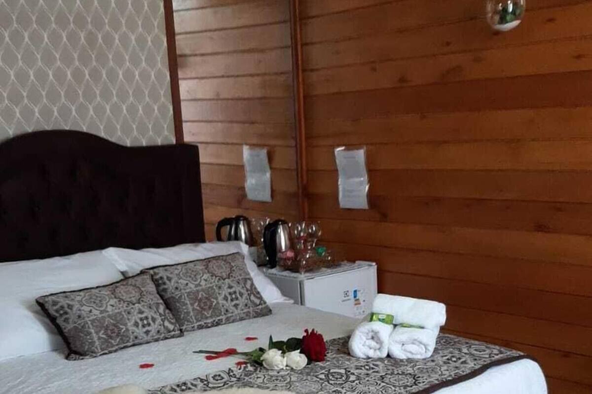Une chambre à coucher avec un lit, un lustre, une table de chevet et une chaise blanche.