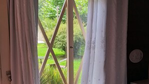 A room with a large window, a round wooden table, a small stool, and a white pouf. - POUSADA REQUINTE SERRANO (Urubici)