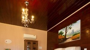 A bedroom with a large bed, a chandelier, a wooden ceiling, a painting, and a cowhide rug. - POUSADA REQUINTE SERRANO (Urubici)