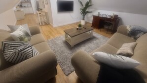 Una sala de estar con un sofá, una mesa de centro y un televisor montado en la pared.