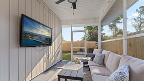 Un patio techado con una televisión montada en la pared, un sofá y una mesita.