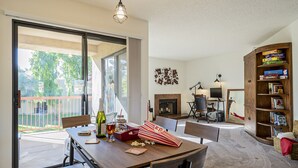 A modern living room with a dining area, a fireplace, and a bookshelf.
