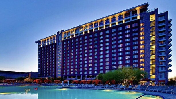 A large hotel with a swimming pool in front.