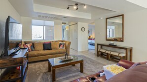 A living room with a brown sofa, a coffee table, a TV, and a large mirror.