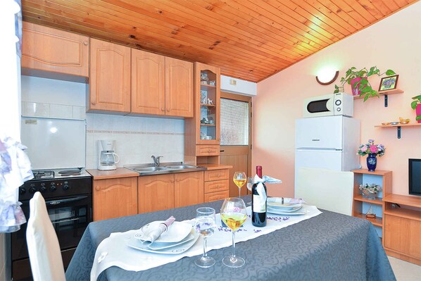 A kitchen with wooden cabinets, a stove, and a dining area with a table set for two.