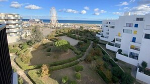 Un immeuble d’appartements moderne offrant une vue sur une plage et une grande roue au loin.