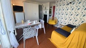 Un espace de vie compact comprenant un coin repas, un canapé et un mur décoré de motifs.