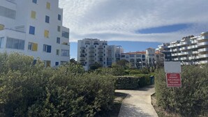 Un chemin mène à un ensemble immobilier moderne composé de plusieurs étages et agrémenté de balcons.