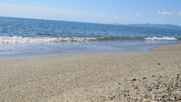 Une plage au rivage de galets et à la mer calme.