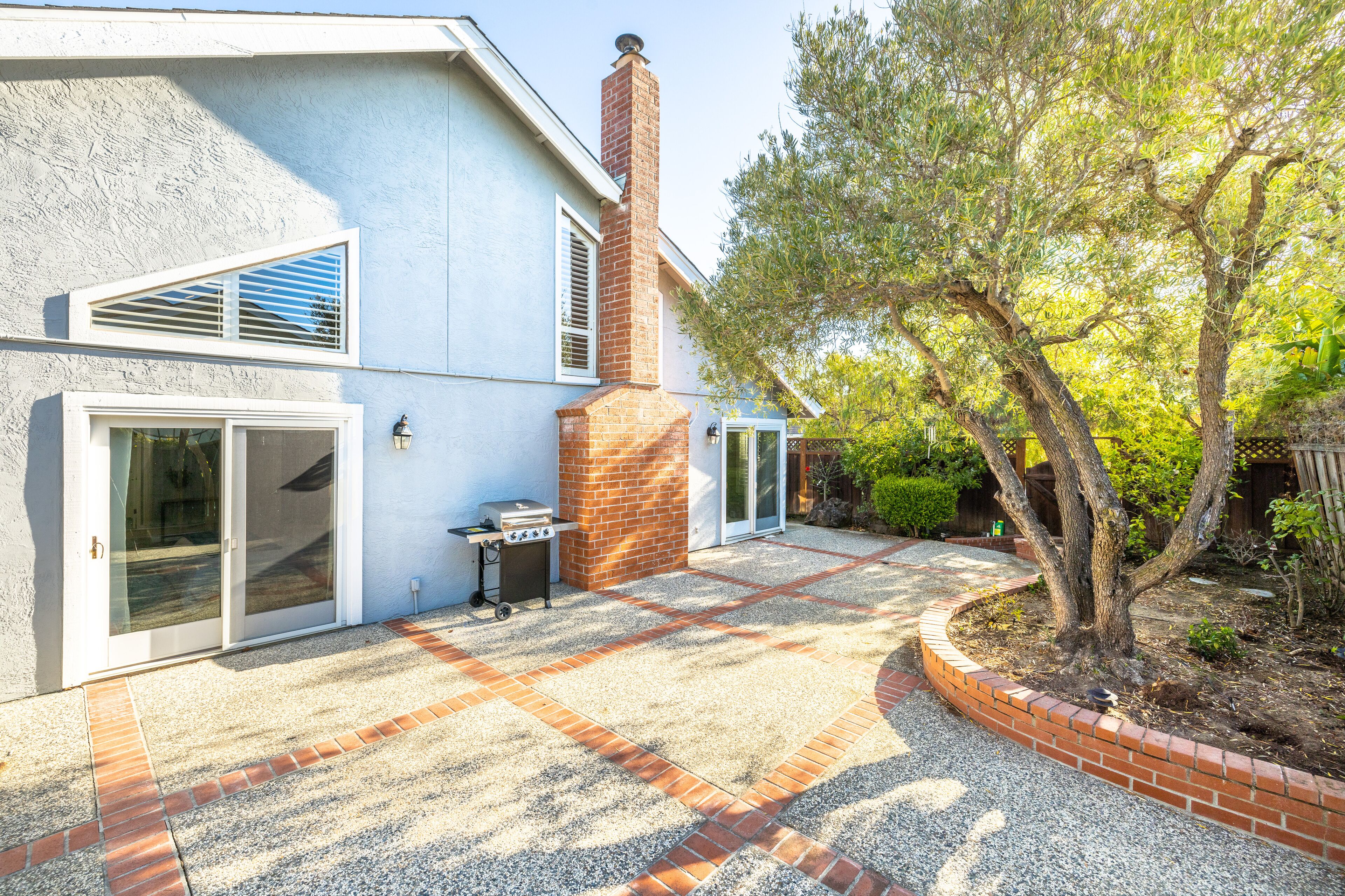 A house with a patio, a brick chimney, and a tree.