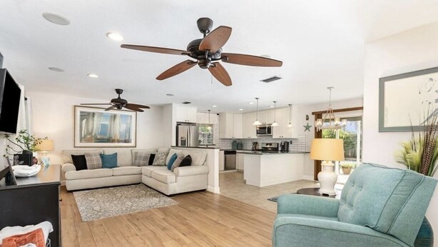 Un salon moderne avec un canapé, un fauteuil turquoise et un ventilateur de plafond.