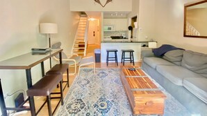 Ein modernes Wohnzimmer mit einer Couch, einem Couchtisch und einer Treppe, die zur Küche führt.