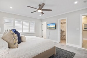 Un dormitorio con cama, ventilador de techo, un cuadro y vestidor.