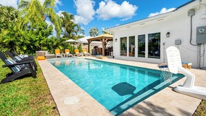 En swimmingpool med liggestole og en overdækket patio.