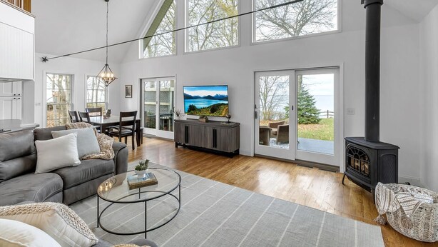 A spacious living room with a fireplace, large windows, and a cozy seating area. - HOT TUB | Lake Front | Lavender Home (Burt)