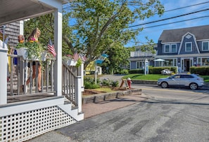 A residential street with a porch, American flags, and a red fire hydrant.